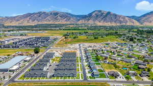 Aerial view of property and surrounding area featuring a mountainous background and nearby suburban area