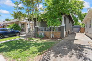 View of front of house with brick siding, a front lawn, an outdoor structure, covered porch, and a garage