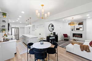Dining space featuring recessed lighting, a fireplace, light wood finished floors, and a chandelier