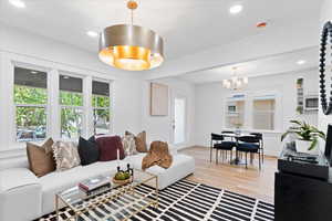 Living room with plenty of natural light, light wood-style flooring, recessed lighting, and a chandelier