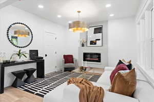Living room with a large fireplace, wood finished floors, and recessed lighting