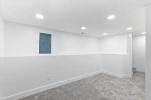 Finished below grade area featuring electric panel, carpet, and recessed lighting