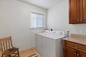 Washroom featuring cabinet space and independent washer and dryer