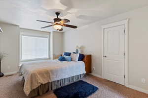 Carpeted bedroom with ceiling fan and a textured ceiling