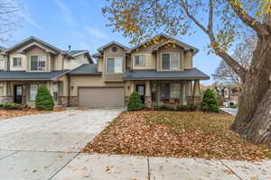 Craftsman-style house featuring stone siding, a porch, driveway, and a shingled roof