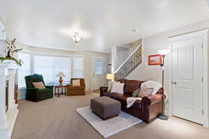 Carpeted living room with a fireplace with raised hearth and stairs