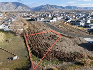 Aerial perspective of suburban area featuring property parcel outlined and a mountainous background