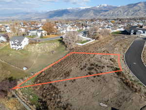 Aerial view of residential area with property boundaries highlighted and a mountain backdrop