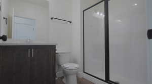Bathroom featuring vanity, a stall shower, and dark wood-type flooring