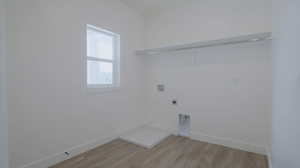 Washroom with hookup for a washing machine, light wood-type flooring, and electric dryer hookup