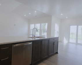 Kitchen featuring stainless steel dishwasher, light stone countertops, dark brown cabinets, light wood-style floors, and open floor plan