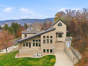 Side view of property with a garage, concrete driveway, a mountain view, and stucco siding