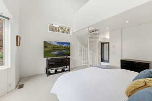 Carpeted bedroom with recessed lighting, a high ceiling, and natural light