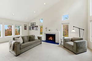 Living room featuring carpet flooring, high vaulted ceiling, a lit fireplace, and recessed lighting