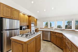 Kitchen with appliances with stainless steel finishes, light countertops, recessed lighting, and brown cabinetry
