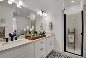 Full bath featuring a marble finish shower, double vanity, light tile patterned flooring, and recessed lighting