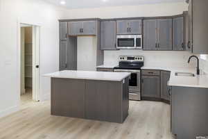 Kitchen featuring appliances with stainless steel finishes, a kitchen island, light wood finished floors, light stone countertops, and recessed lighting