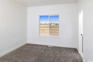 Spare room featuring baseboards and dark colored carpet