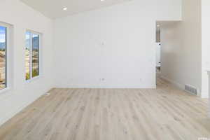 Empty room with light wood-style floors and recessed lighting
