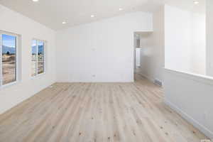 Unfurnished room with light wood-type flooring, recessed lighting, and lofted ceiling
