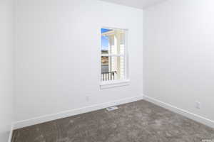 Empty room featuring baseboards and dark carpet