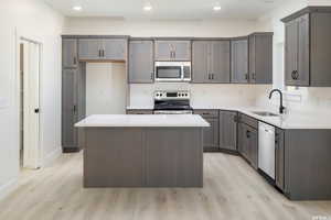 Kitchen featuring stainless steel appliances, a center island, light wood-style flooring, recessed lighting, and light stone countertops
