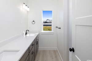 Bathroom with double vanity and light wood-style flooring