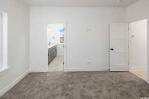 Unfurnished bedroom featuring light carpet and ensuite bathroom