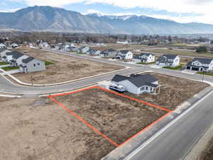 Aerial view of residential area with property boundaries highlighted and a mountain backdrop
