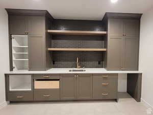 Bar area featuring open shelves, gray cabinets, tasteful backsplash, and light stone countertops