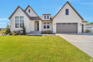 Modern farmhouse style home with driveway, a garage, a front yard, and brick siding