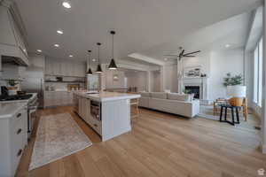 Kitchen with pendant lighting, ceiling fan, a breakfast bar area, high quality appliances, and custom exhaust hood