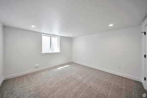 Empty room with light carpet and recessed lighting