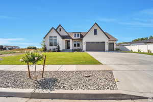 Modern farmhouse with driveway, stucco siding, and a garage