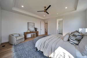 Bedroom with a tray ceiling, wood ceiling, wood finished floors, ceiling fan, and recessed lighting