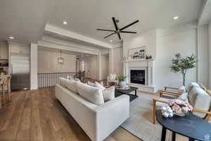 Living area featuring a glass covered fireplace, light wood-style flooring, recessed lighting, ceiling fan, and a chandelier