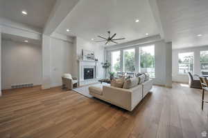 Great room featuring light wood finished floors, a glass covered fireplace, recessed lighting, and a ceiling fan