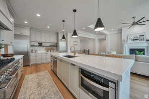 Kitchen with pendant lighting, premium appliances, light stone countertops, a glass covered fireplace, and recessed lighting