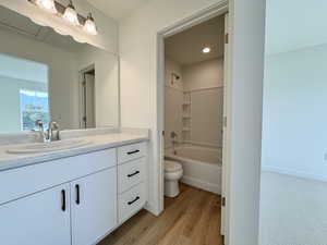 Full bath featuring vanity, washtub / shower combination, and light wood-style floors