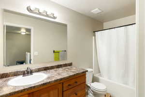 Bathroom featuring vanity, shower / bath combo, and a textured ceiling