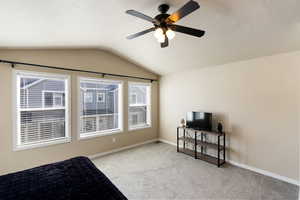 Bedroom with vaulted ceiling, light colored carpet, and a ceiling fan