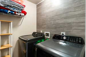 Laundry room with an accent wall and washer and clothes dryer