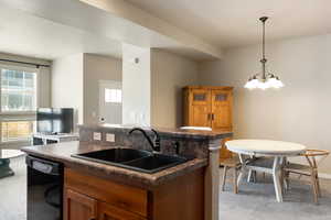 Kitchen featuring brown cabinets, light colored carpet, and dark countertops