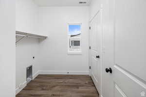Laundry area with dark wood-style floors and hookup for an electric dryer