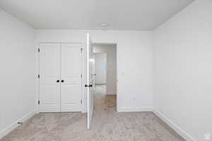 Unfurnished bedroom with light colored carpet and a closet