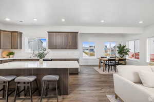 Kitchen featuring dark brown cabinetry, a kitchen bar, dark wood-style floors, recessed lighting, and a kitchen island