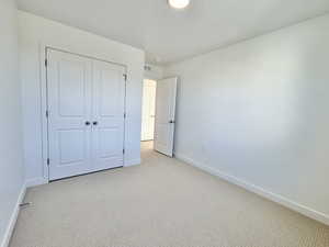 Unfurnished bedroom with carpet, a textured ceiling, and a closet