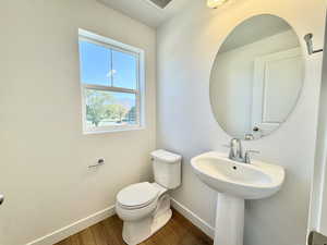 Half bath with baseboards and wood finished floors