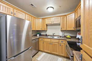 Kitchen featuring stainless steel appliances, a textured ceiling, and dark countertops