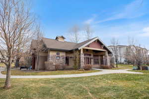 View of front of property featuring a front lawn, stone siding, and a shingled roof